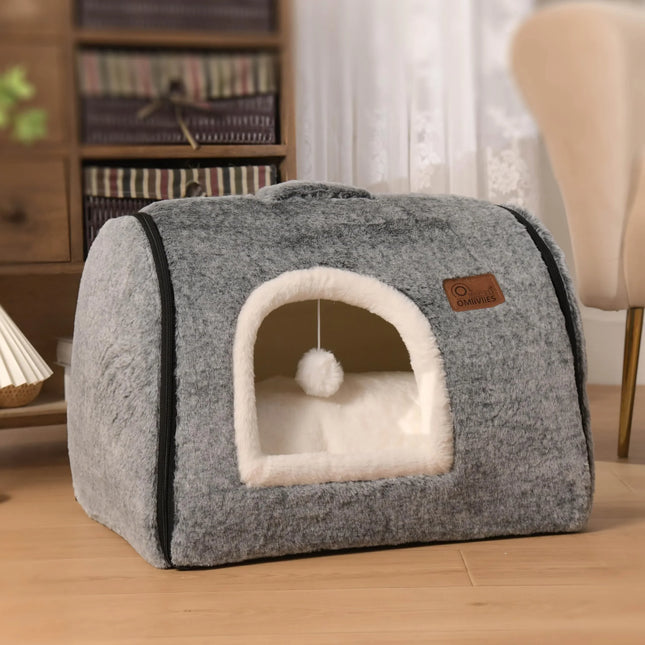 Cozy gray cat bed with plush white interior and hanging pom-pom toy, perfect for indoor pets.