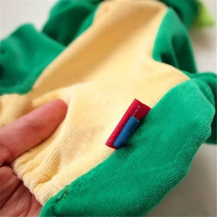 Close-up of the soft yellow interior lining and red tag of a green dinosaur costume for dogs.
