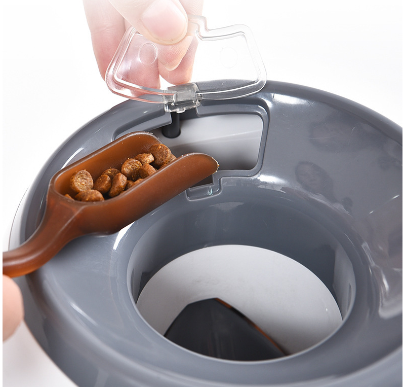 Pet food dispenser with scoop pouring dry kibble into gray automatic feeder for dogs and cats