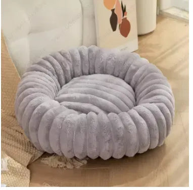 Round plush grey pet bed for dogs and cats on a wooden floor.
