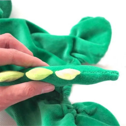 A person's hand touching the green fabric and yellow scales of a dinosaur costume for dogs.