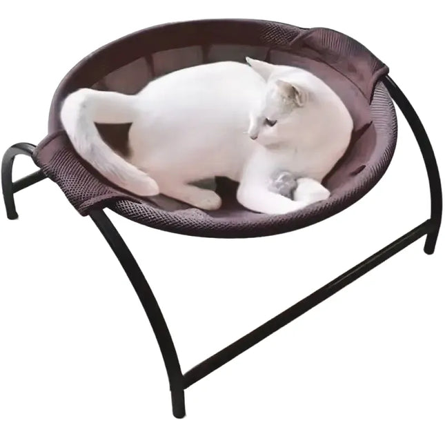 White cat relaxing in a TM elevated cat hammock bed with a black metal stand.