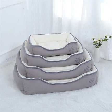 Set of four grey Oxford cloth plush pet beds in different sizes stacked on a white rug.