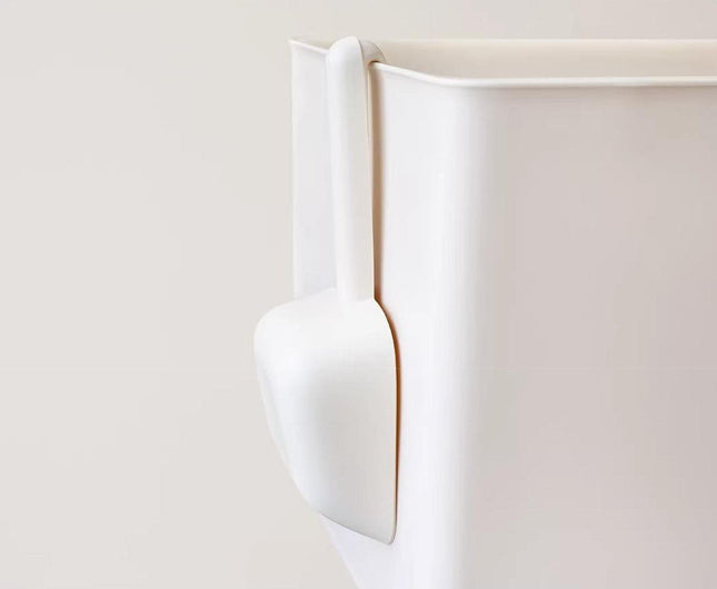 White pet food scoop attached to storage container for dog or cat food